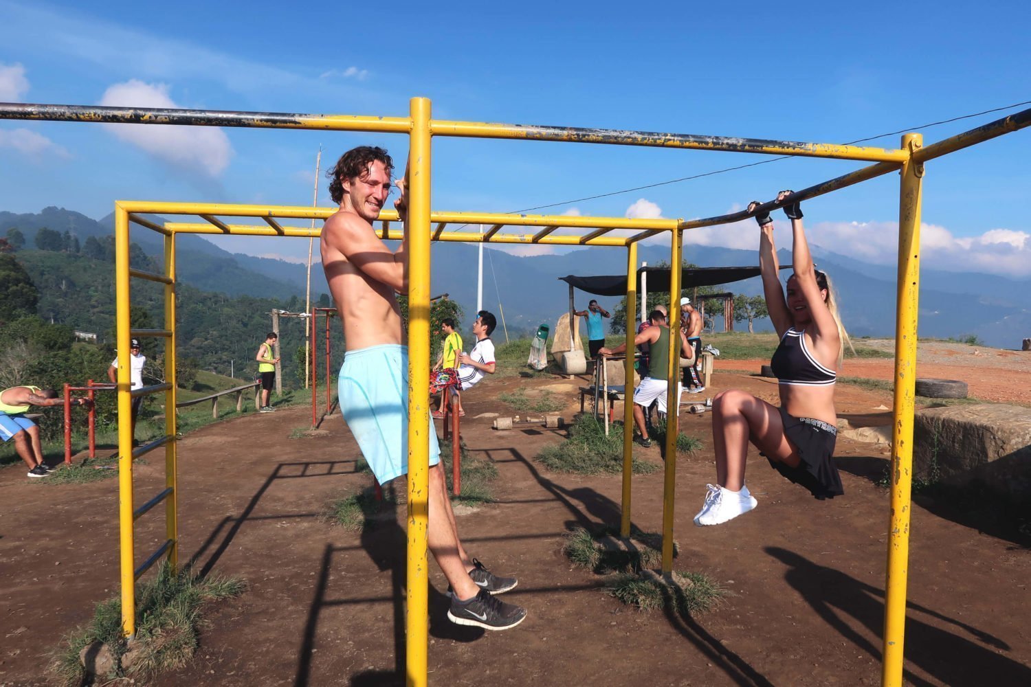 chris and juliana hanging on the bars at the outdoor gym at the top of cerro las tres cruces