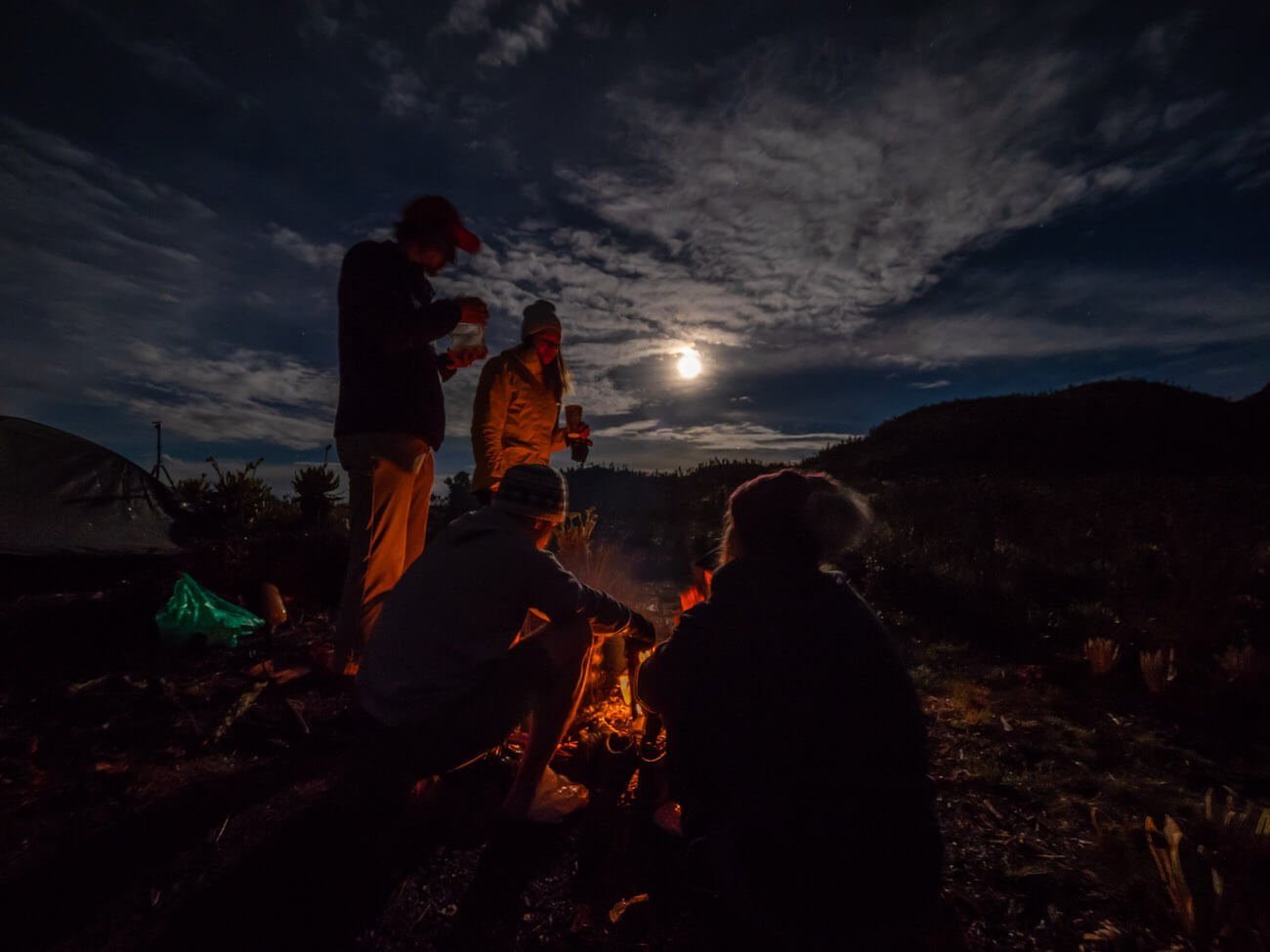 Huddled around campfire with moon behind us