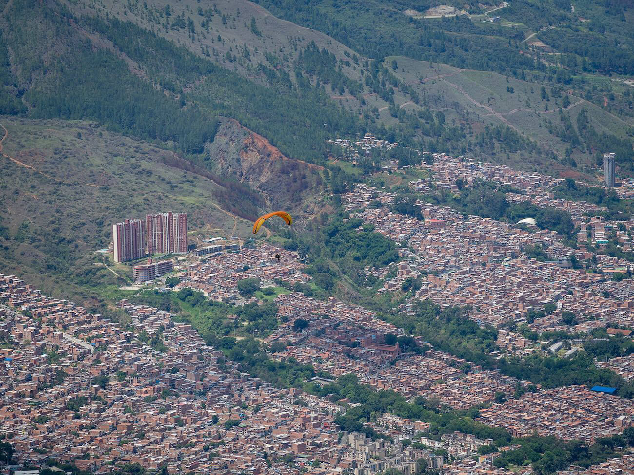 Paraglider in sky with city below