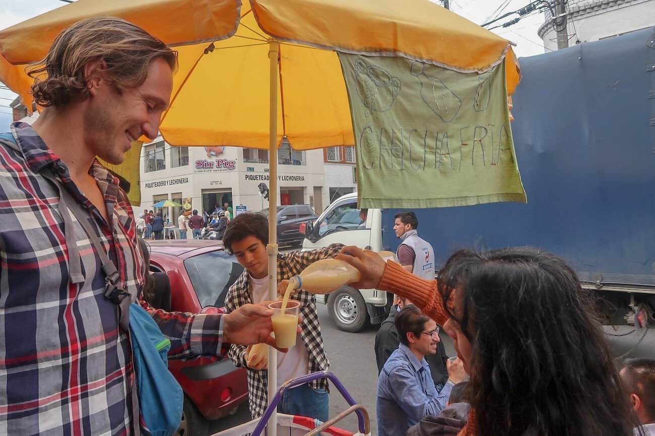 A street vendor pouring chicha, a traditional Colombian drink, for Chris