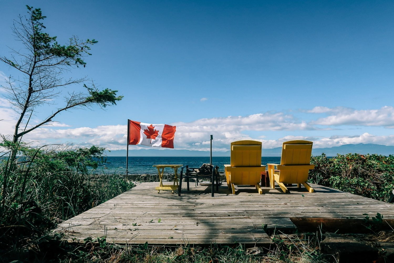 Cover image for the Savary Island travel guide: A pair of deck chairs on the beach with a flapping Canadian flag.