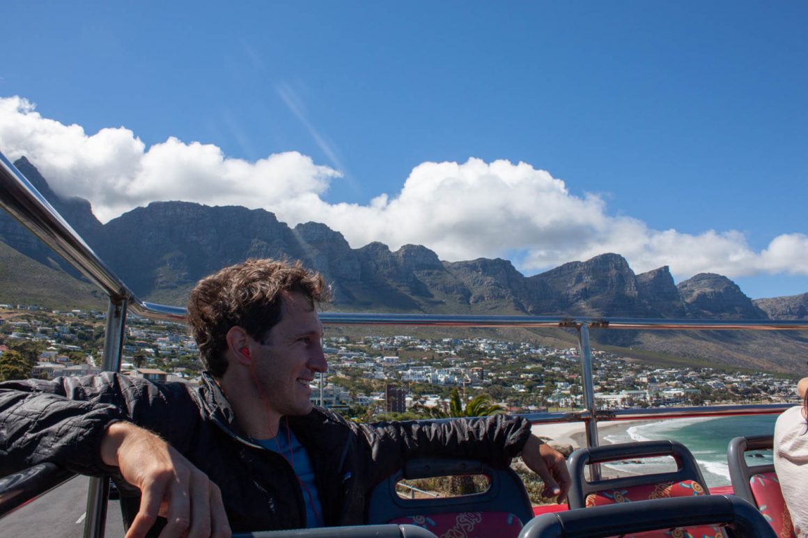 Chris chilling on the back of the hop-on hop-off bus with the Twelve Apostles in the background
