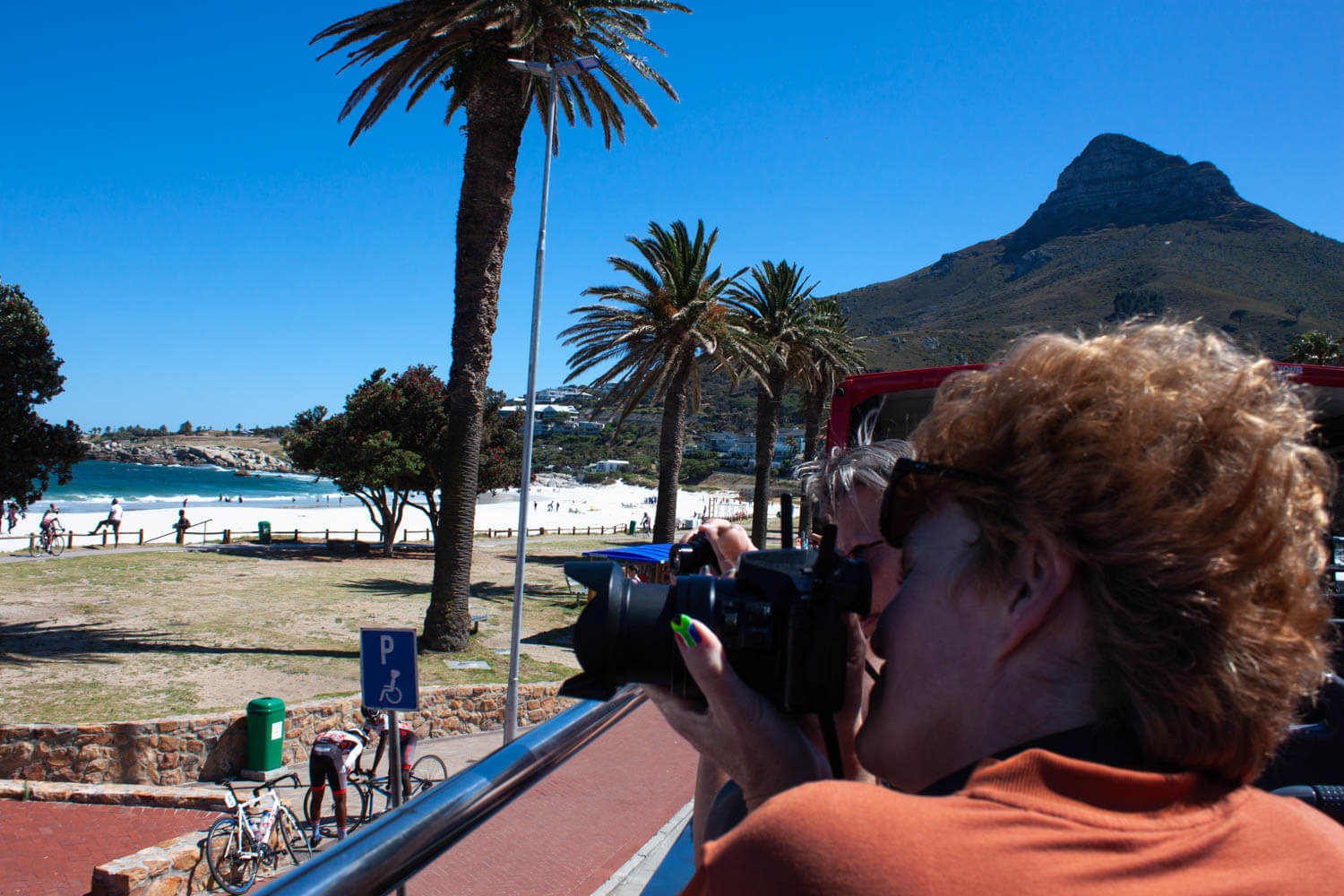Lady taking photo of Camps Bay with Lions Head in background