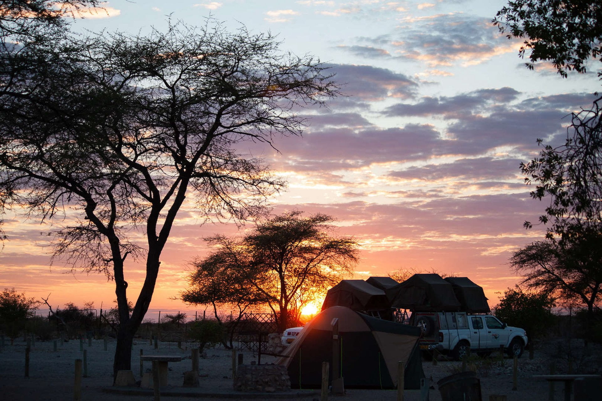 Sunrise at Okaukuejo Camp in Etosha with camper trucks in the foreground.