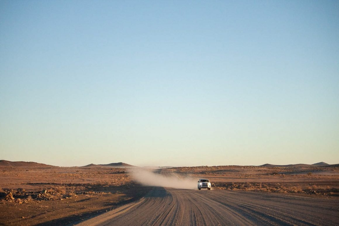 Truck at sunrise speeding across the gravel roads in Fish River Canyon