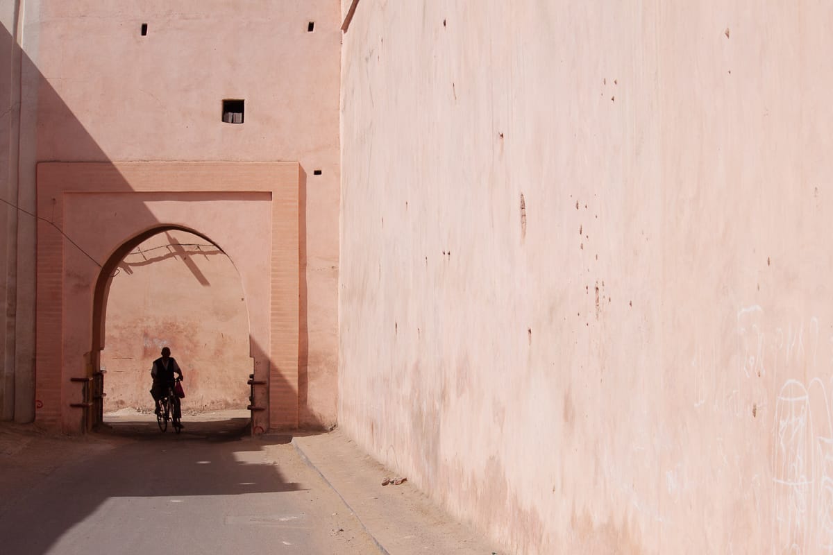 Pink entrance to medina with cyclist in the middle.